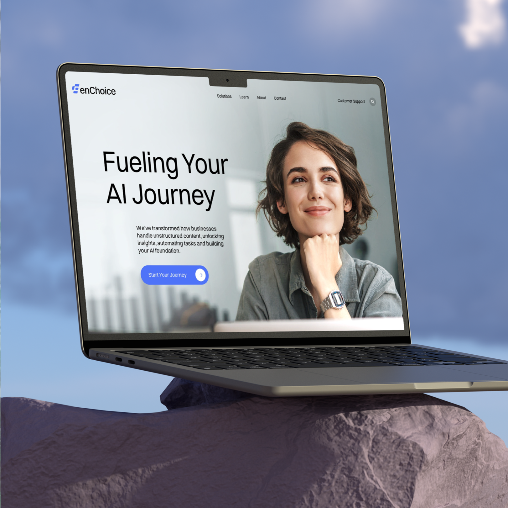 Laptop on a rock showing the enChoice homepage, “Fueling Your AI Journey”